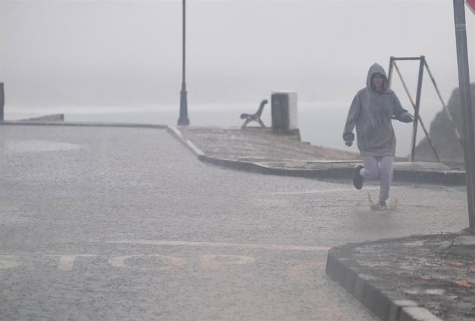 Archivo - Una persona corre por las fuertes lluvias registradas en el norte de Fuerteventura con motivo de la llegada de un temporal a la isla, en El Cotillo, Fuerteventura, Canarias, (España), a 5 de febrero de 2021.