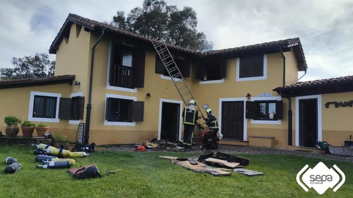 Bomberos trabajan en la extinción de un incendio en una vivienda de Llanes.