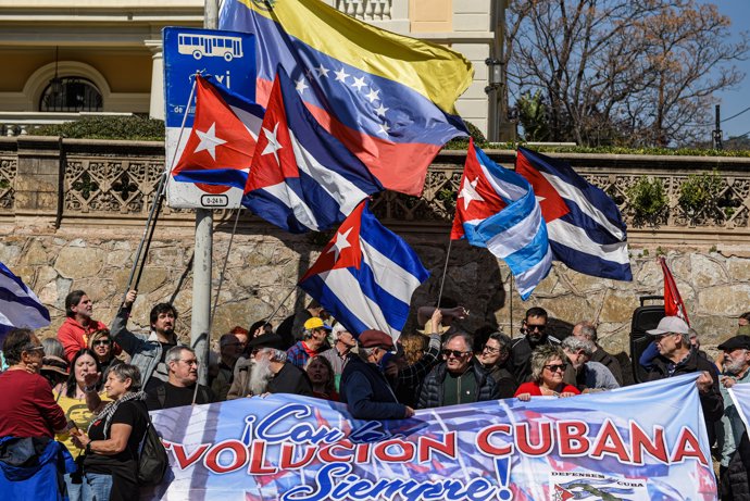 Manifestantes portan pancarta con lema 'Con la revolución cubana siempre' durante una concentración en apoyo de Cuba, ante el Consulado de EE.UU., a 21 de marzo de 2026, en Barcelona, Catalunya (España).