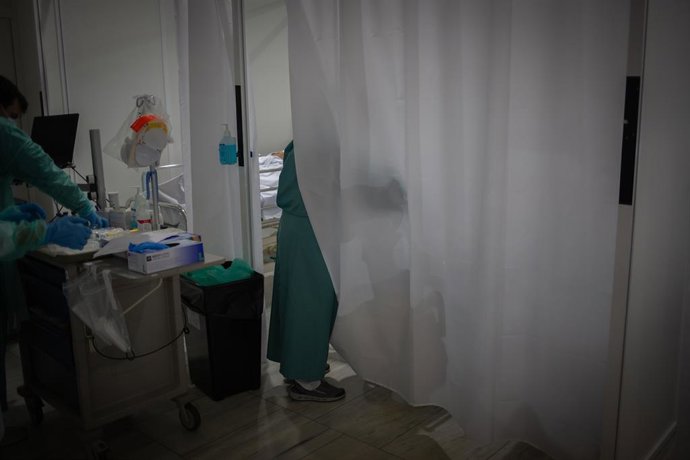 Archivo - Arxivo - Un sanitari visita a un dels malalts ingressat en un dels boxes de la Unitat de Vigilància intensiva ?UCI- de l'Hospital de la Santa Creu i Sant Pau, integrat a la Xarxa Hospitalària d'Utilització Pública de Catalunya, a Barcelona (arch