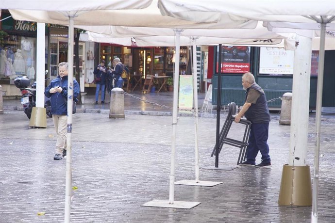 Archivo - Un camarero saca las sillas de la terraza en Sevilla en imagen de archivo.