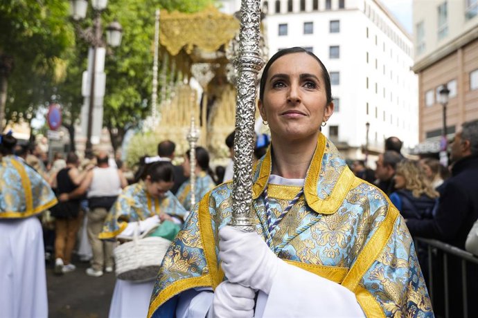 Archivo - Una acólita porta un cirial delante del paso de la Virgen de la Aurora, de la hermandad de la Resurrección de Sevilla, a su paso por la Plaza del Duque, en una foto de archivo.