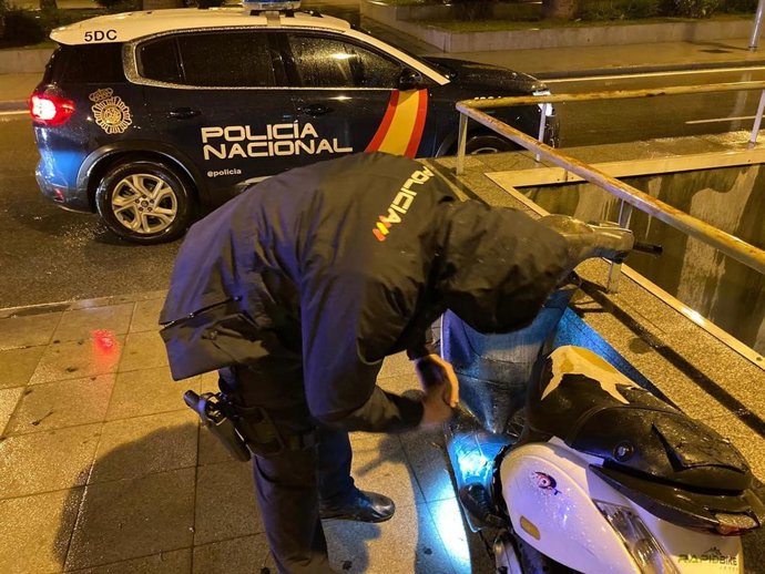 Un agente de la Policía Nacional inspecciona uno de los vehículos dañados.