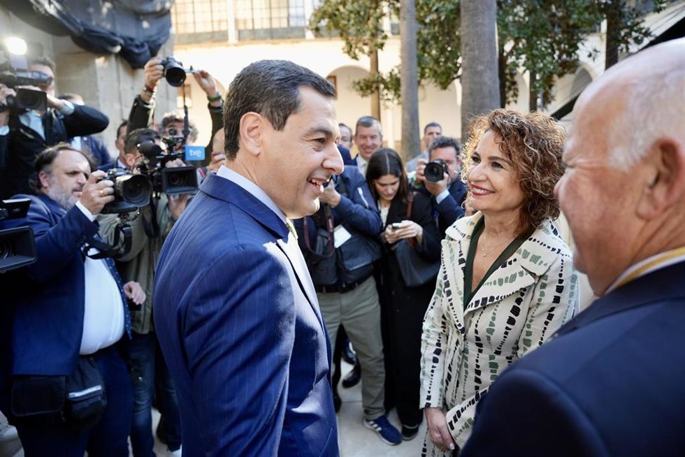 La vicepresidenta primera y ministra de Hacienda y candidata a la Junta de Andalucía del PSOE-A, María Jesús Montero saluda al presidente de la Junta de Andalucía, Juanma Moreno (d) a su llegada al acto del Día de Andalucía. A 28 de febrero de 2026