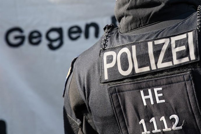 Archivo - 11 June 2021, Hessen, Frankfurt_Main: Thw word "Against" is written in German on a poster held by demonstrators, next to a policeman during a demonstration by left-wing alliances against right-wing structures in the police, following the disband