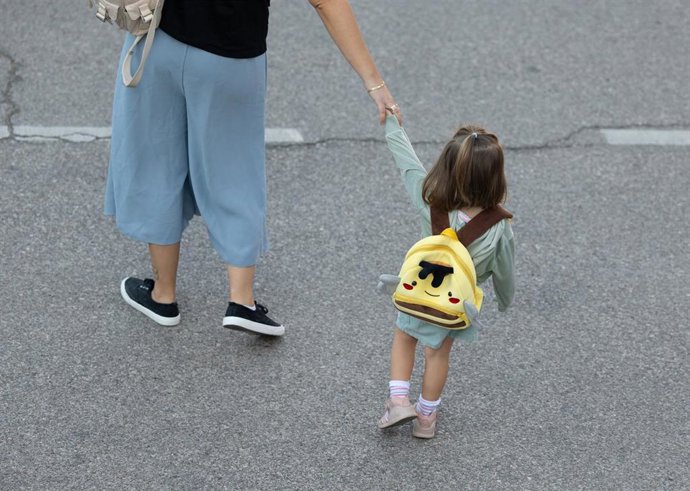 Archivo - Una niña junto a su madre en la entrada de un colegio.