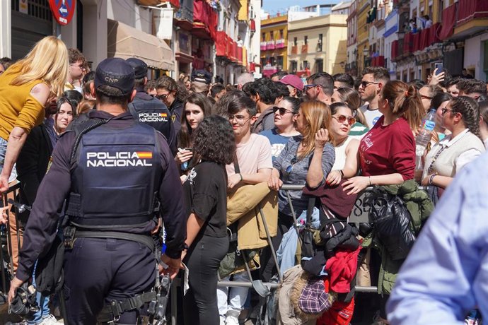Archivo - Agentes de la Policía Nacional contralan a la multitud concentrada en Pureza para ver la cofradía de la Esperanza de Triana, en foto de archivo.