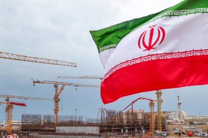 Archivo - Una bandera de Irán frente a unas obras en la central nuclear de Bushehr (archivo)