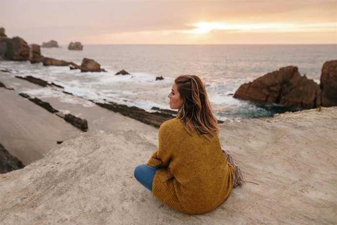 Mujer joven sentada junto al mar