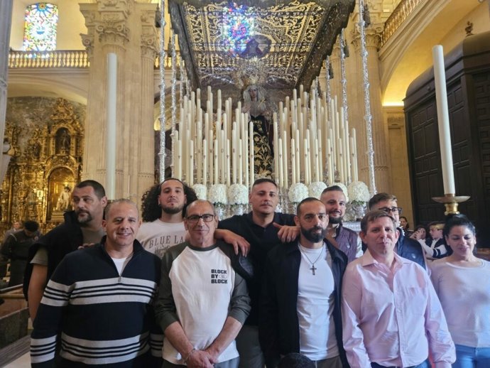 Un grupo de internos del centro penitenciario Sevilla I coloca los lazos del paso del Cristo del Amor y realiza una ofenda floral.