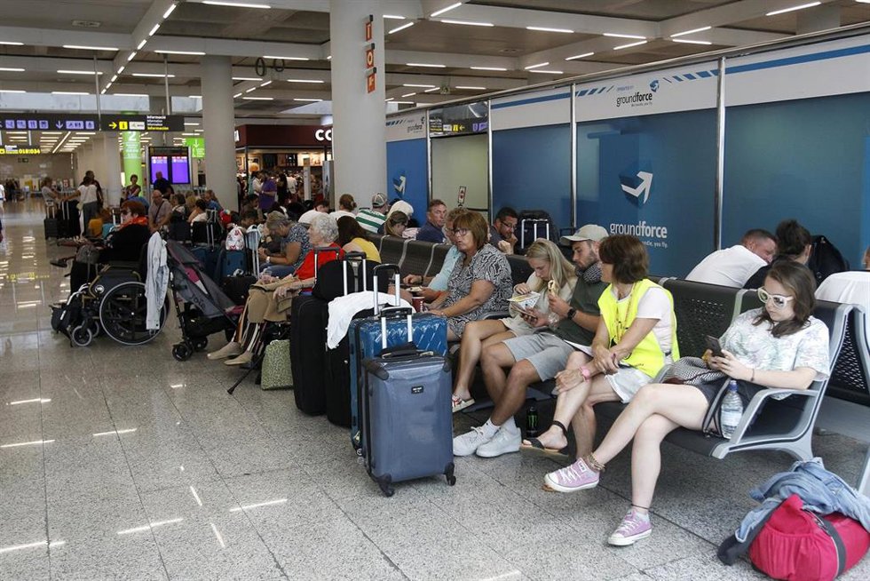 Archivo - Varios turistas esperan sentados con sus maletas en el aeropuerto de Palma.