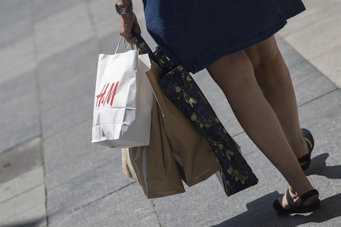 Archivo - Una mujer pasea cargada con varias bolsas, una de ellas perteneciente a la tienda H&M, durante el segundo día de rebajas, en Madrid (España), a 26 de junio de 2020. La cadena textil sueca Hennes & Mauritz (H&M) registró pérdidas de 476 millones 