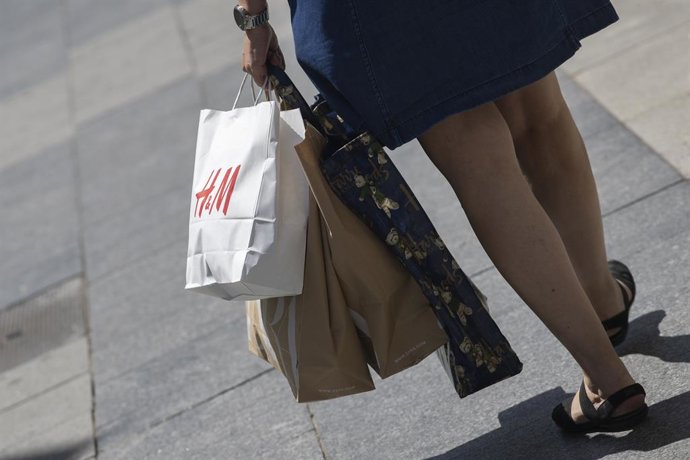 Archivo - Una mujer pasea cargada con varias bolsas, una de ellas perteneciente a la tienda H&M, durante el segundo día de rebajas, en Madrid (España), a 26 de junio de 2020. La cadena textil sueca Hennes & Mauritz (H&M) registró pérdidas de 476 millones 