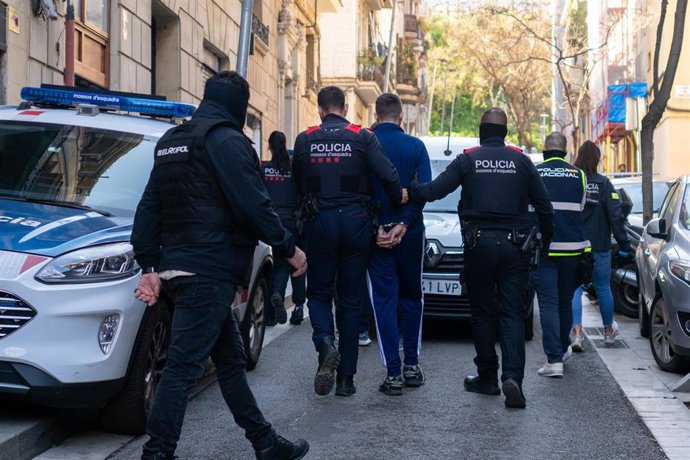 Agentes de los Mossos d'Esquadra se lleva a un detenido durante un operativo policial contra el tráfico internacional de armas y drogas, a 23 de marzo de 2026, en Barcelona, Catalunya (España)