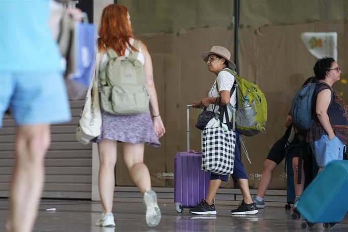 Archivo - Varias personas con maletas