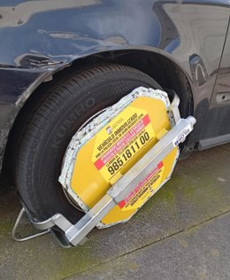 Cepo colocado en vehículos denunciados por estacionamiento indebido en Gijón, que no puede retirar la grúa.