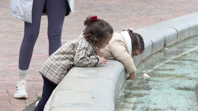 Niñas jugando con el agua de una fuente.