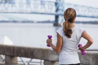 Archivo - Mujer caminando con pesas.