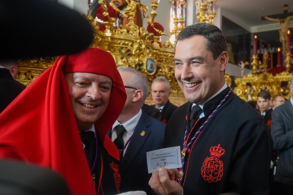 Archivo - El presidente de la Junta de Andalucía, Juanma Moreno muestra su papeleta de sitio antes de empezar la estación de penitencia del Santísimo Cristo de la Exaltación a 5 de abril de 2023 en Málaga