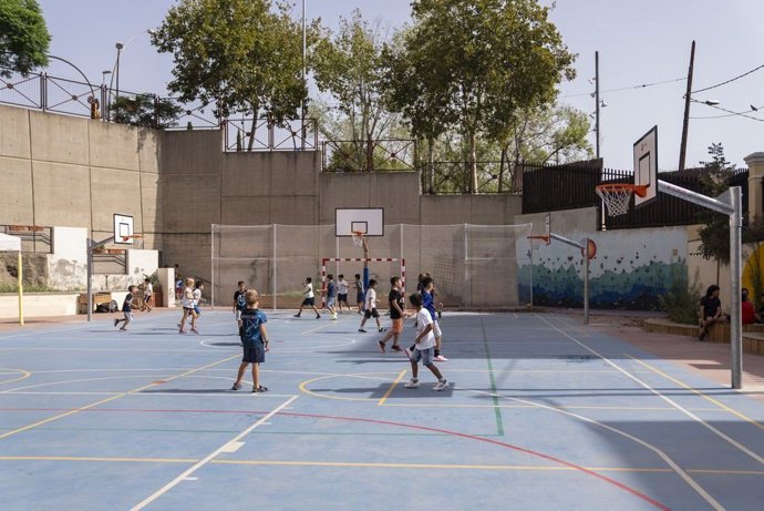 Archivo - Niños jugando a futbol en el patio de una escuela
