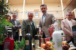El consejero de Agricultura, Pesca, Agua y Desarrollo Rural de la Junta, Ramón Fernández-Pacheco, coge una botella de aceite en su visita al Consejo Regulador de la DOP Baena.
