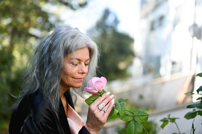 Archivo - Mujer oliendo una rosa.
