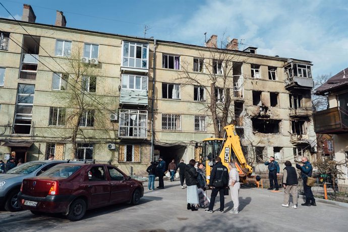 March 26, 2026, Dnipro, Dnipropetrovsk Oblast, Ukraine: Police and locals stand before a Dnipro residential block hit by a Russian drone on March 26, 2026. Heavy machinery and emergency services were deployed to the site to clear rubble and prevent furthe