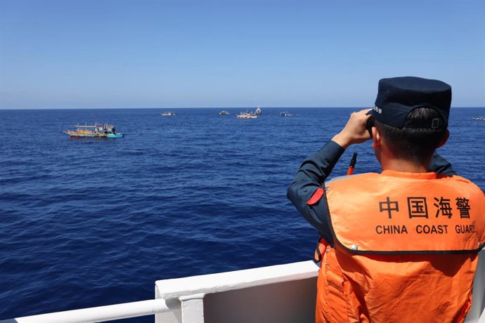 SOUTH CHINA SEA, March 1, 2026  -- A law enforcer of China Coast Guard (CCG) vessel Wanshan observes Philippine vessels in waters off China's Huangyan Dao in the South China Sea, Feb. 27, 2026. The CCG on Friday drove away Philippine vessels that illegall