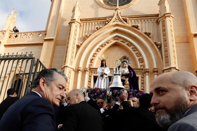 El consejero de Sanidad, Presidencia y Emergencias de la Junta de Andalucía, Antonio Sanz, toca la campana de las andas del traslado del Cautivo de Málaga y la Virgen de la Trinidad.