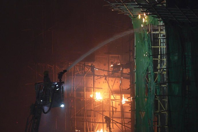 Archivo - Arquivo - 26 de novembro de 2025, Hong Kong, China: Um bombeiro em uma escada lança água enquanto um grande incêndio atinge vários prédios residenciais em Wang Fuk Court, em 26 de novembro de 2025, em Hong Kong. Vários prédios residenciais em Wa
