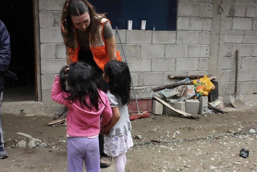 Joven cooperante acompañando a dos menores.