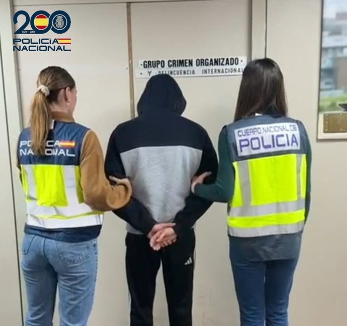 El detenido, de espaldas y custodiado por dos agentes de la Policía Nacional.