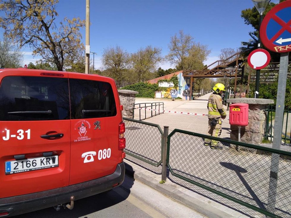 Un Bombero de Zaragoza frente a una de las zonas verdes de la ciudad cerradas al público por las fuertes rachas de viento que siguen soplan este domingo.