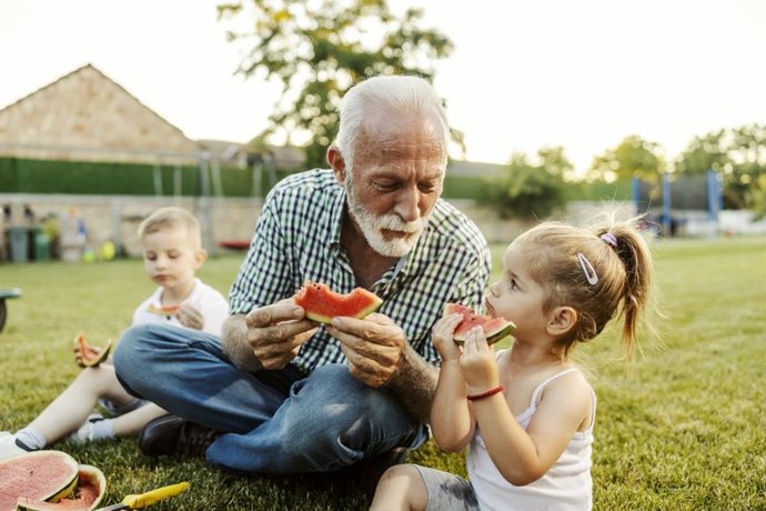 Archivo - Niños felices con su abuelo comiendo sandía. Nietos, abuelo