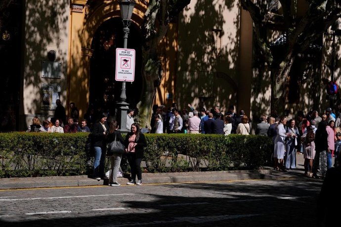 Viandantes en Sevilla durante el Domingo de Ramos 2026 junto a una señal de seguridad.