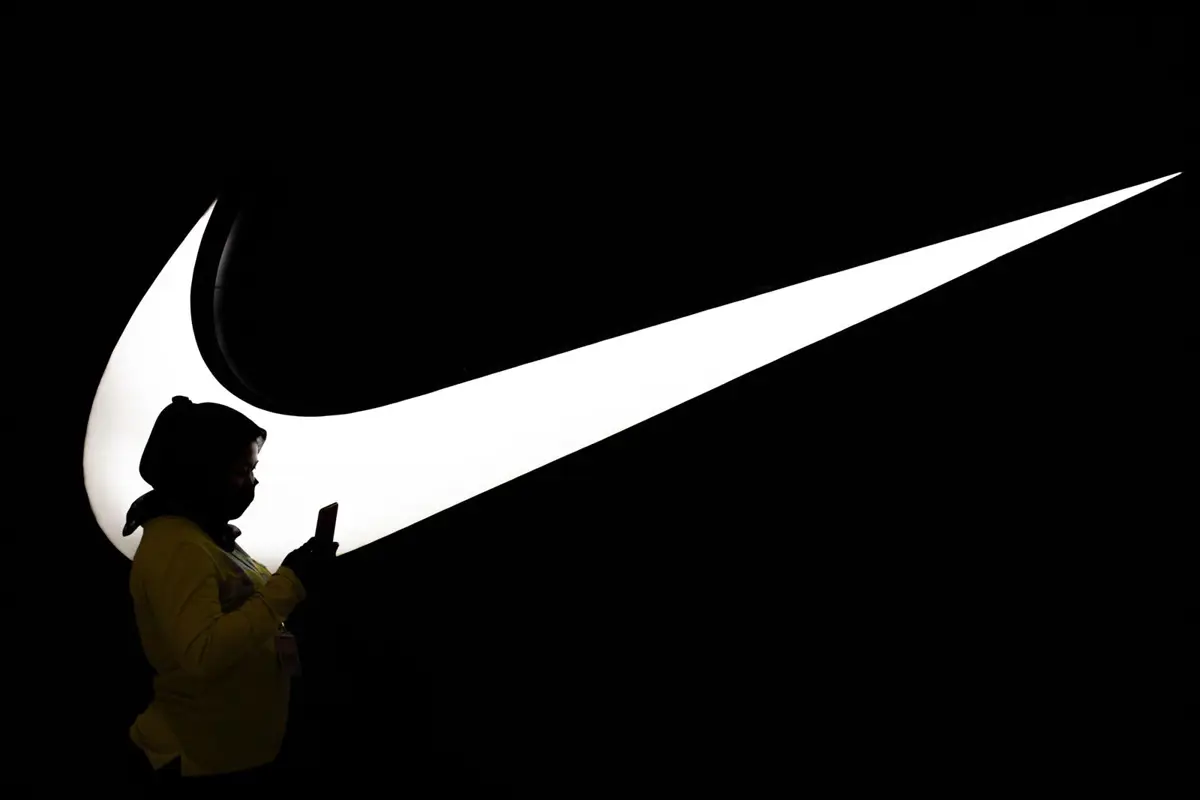 Mujer caminando frente al logo de Nike en Yakarta (Indonesia)