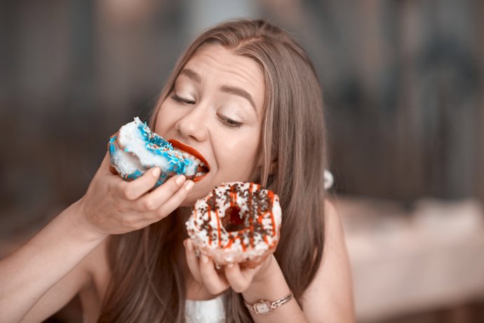 Mujer comiendo dulces con ansiedad.