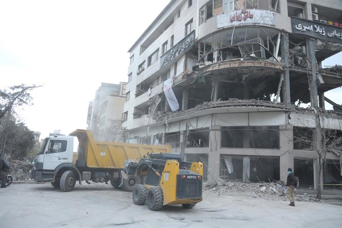 TEHRAN, March 30, 2026  -- This photo taken on March 29, 2026 shows vehicles removing debris outside the building that houses the offices of the Qatari Al Araby TV after a missile strike in Tehran, Iran. The Qatari Al Araby TV said on Sunday that its offi
