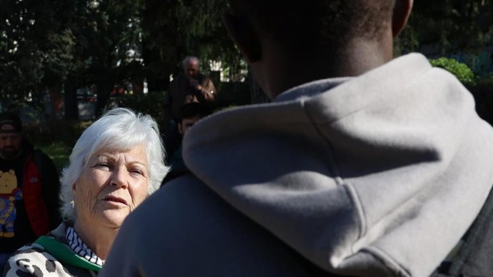 La presidenta de la ONG Somos Acogida, Emilia Lozano, junto a un joven migrante en el parque Isabel Clara Eugenia de Hortaleza (Madrid)