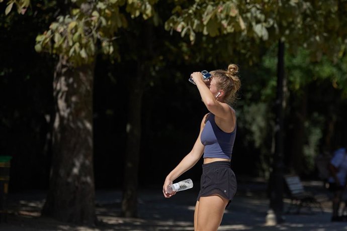 Archivo - Una mujer con una botella de agua en el parque de El Retiro.