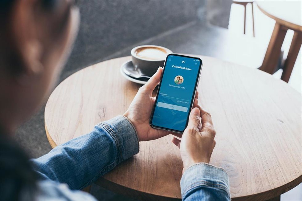 Archivo - Imagen de archivo de una persona con la aplicación de CaixaBank en su móvil