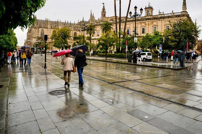 Imagen de archivo de viandantes caminando en Sevilla en una jornada marcada por las lluvias.