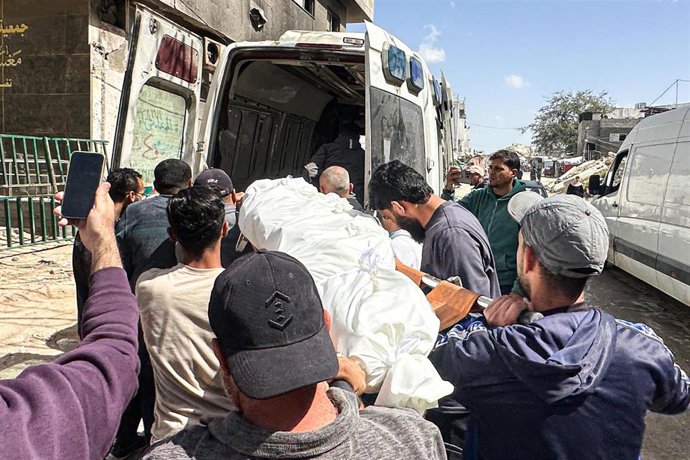 Varios palestinos ayudan a desplazar el cuerpo de una víctima mortal en un ataque israelí