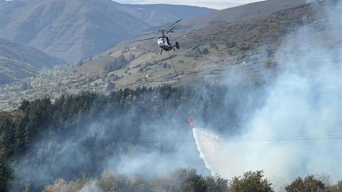 Archivo - Un helicóptero trata de apagar el incendio forestal en Arenas de Iguña en foto de archivo