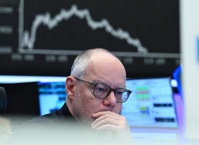Archivo - 03 April 2025, Hesse, Frankfurt/Main: A stock market trader watches his monitors on the trading floor of the Frankfurt Stock Exchange as the display board with the DAX curve shows falling prices. The tariff package announced by US President Trum