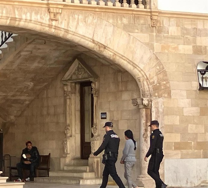 La mujer condenada por asesinar a su bebé arrojándola a un contenedor, de espaldas y escolatada por dos agentes de la Policía Nacional, a su llegada este martes a la Audiencia Provincial de Baleares.