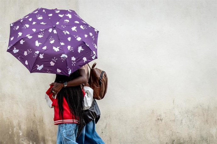 Una pareja pasea con un paraguas en un día de lluvia.