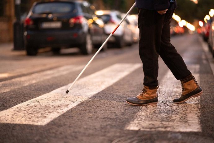Archivo - Pies de una persona ciega cruzando un paso peatonal con su bastón por la noche. Concepto de movilidad para personas con discapacidad visual