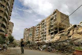 March 25, 2026, Beirut, Beirut, Lebanon: A resident of Beirut southern suburb carrying bags of Manakish, a classic Lebanese flatbread topped with zaA?ââ?atar, cheese, or both, walks past destroyed building  at the edge of the devastated Beirut southern