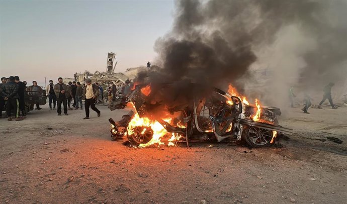 Un grupo de personas frente a los restos de un vehículo bombardeado por Israel en la Franja de Gaza, ataque ejecutado el 8 de abril de 2026 en el que murió un periodista de la cadena de televisión qatarí Al Jazeera